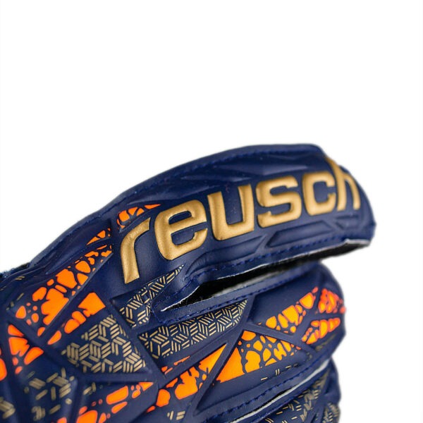 Close-up of the Reusch Attrakt Solid goalkeeper glove showing the embossed Reusch branding and textured backhand design in navy, orange, and gold.