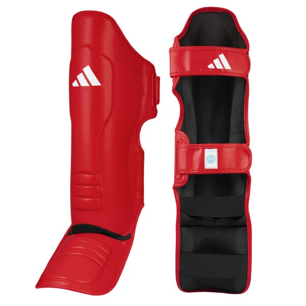Front and inner view of the Adidas WAKO Pro shin guards with integrated in-step protection in red featuring hook-and-loop straps, cushioned lining, and WAKO approved label.